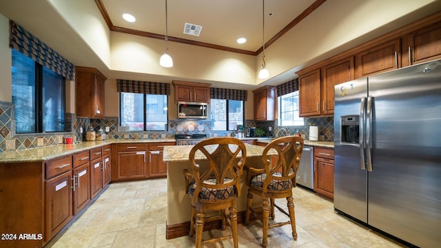 kitchen featuring tasteful backsplash, ornamental molding, a kitchen island, appliances with stainless steel finishes, and pendant lighting