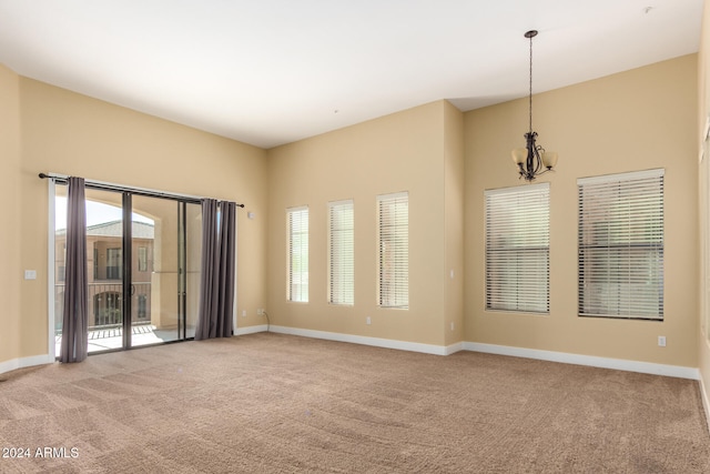 spare room featuring light colored carpet and a notable chandelier