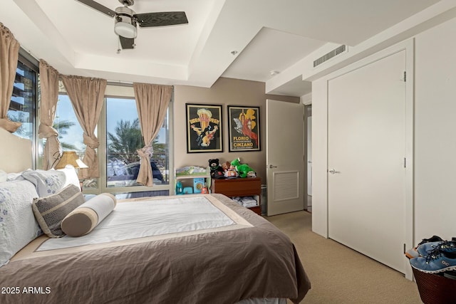 bedroom with light colored carpet, access to outside, and a tray ceiling