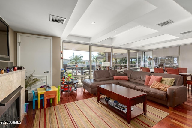 living room featuring a wall of windows, wood finished floors, beamed ceiling, and a fireplace