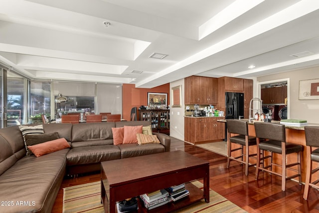 living room with wood finished floors and a raised ceiling