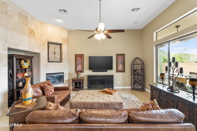 living room featuring ceiling fan, a fireplace, and light tile patterned floors