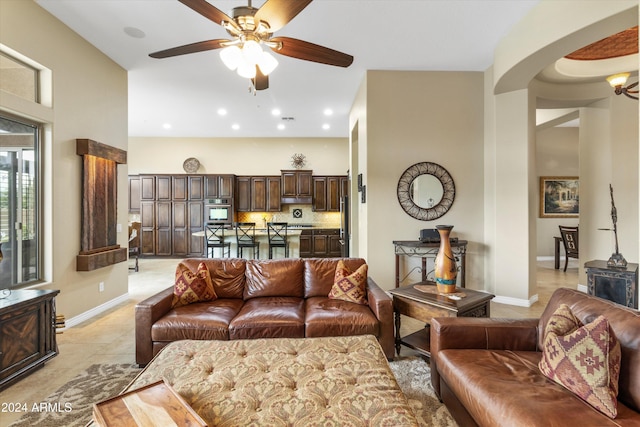 tiled living room with ceiling fan and a high ceiling