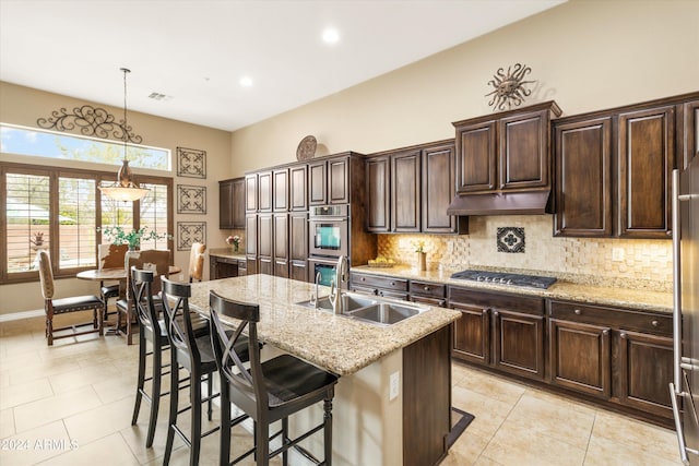 kitchen featuring sink, an island with sink, decorative light fixtures, a kitchen bar, and stainless steel appliances