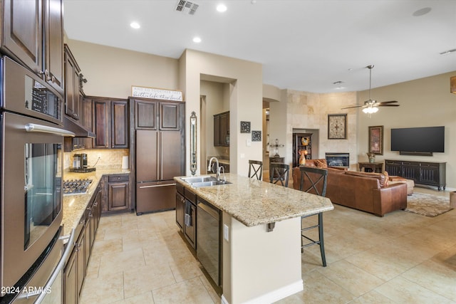 kitchen featuring appliances with stainless steel finishes, sink, a center island with sink, a fireplace, and a breakfast bar area