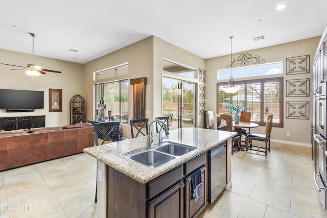 kitchen featuring sink, a breakfast bar area, an island with sink, dark brown cabinetry, and stainless steel appliances