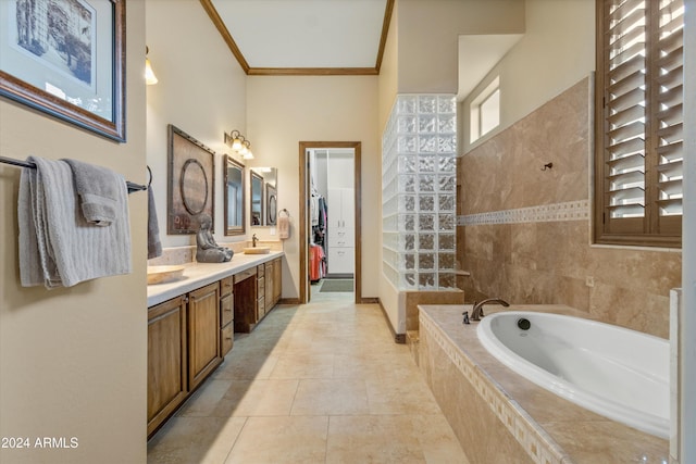 bathroom with tile patterned flooring, vanity, crown molding, and tiled tub