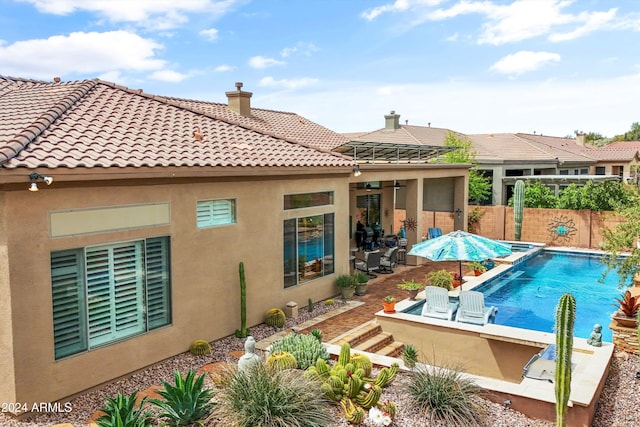 back of property with a fenced in pool and a patio