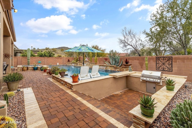 view of pool with pool water feature, a patio area, exterior kitchen, and grilling area