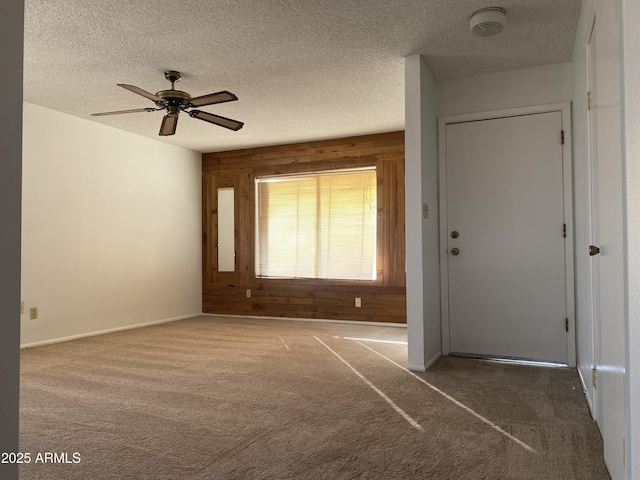 unfurnished room featuring carpet floors, a textured ceiling, and wood walls