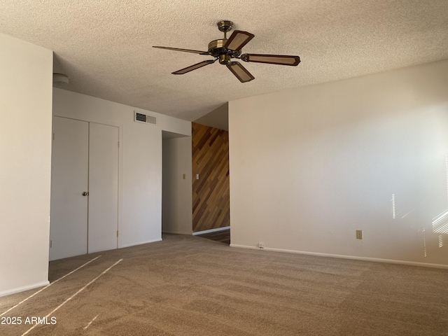 unfurnished bedroom featuring dark colored carpet, ceiling fan, and a textured ceiling