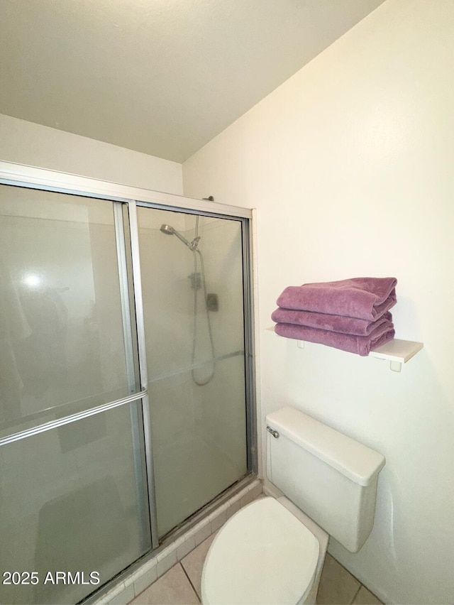 bathroom featuring tile patterned flooring, an enclosed shower, and toilet