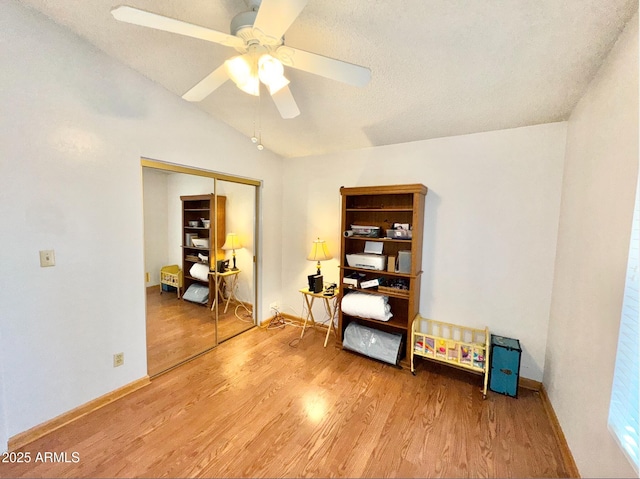 misc room with ceiling fan, lofted ceiling, hardwood / wood-style floors, and a textured ceiling