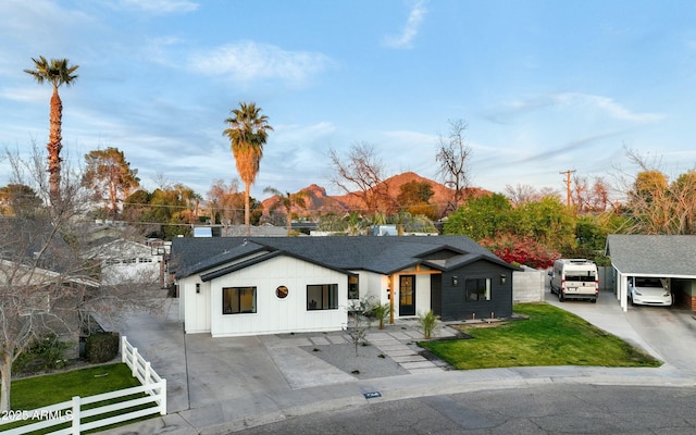 modern farmhouse with a front yard, roof with shingles, driveway, and fence