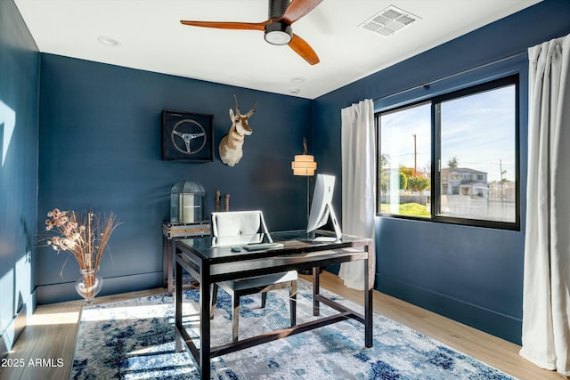 home office featuring ceiling fan, wood finished floors, visible vents, and baseboards