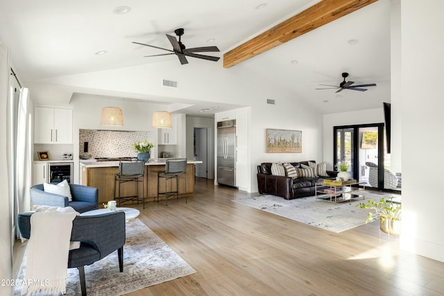 living area with visible vents, ceiling fan, wine cooler, beamed ceiling, and light wood-type flooring