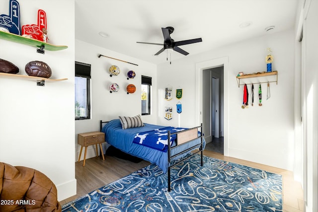 bedroom with wood finished floors, a ceiling fan, and baseboards