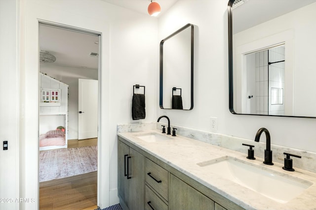 bathroom featuring double vanity, visible vents, a sink, and wood finished floors