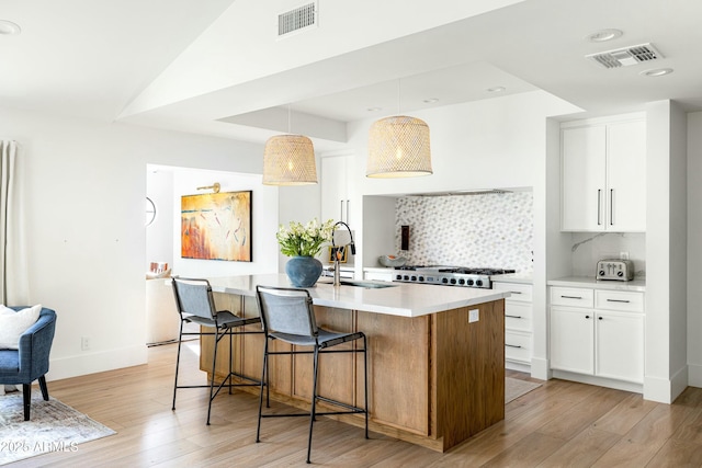 kitchen featuring visible vents, a sink, light wood-style flooring, and stove