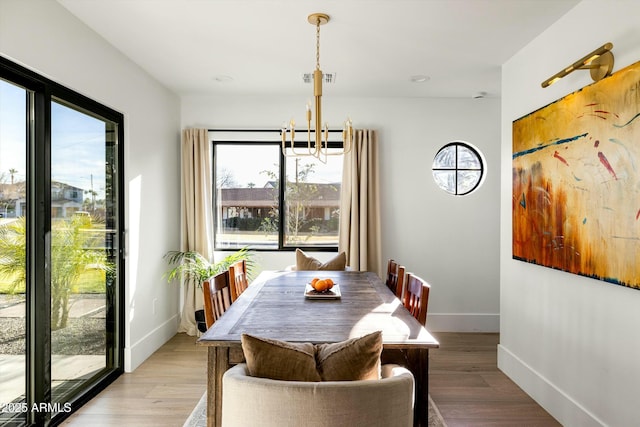 dining space featuring baseboards, a chandelier, and wood finished floors