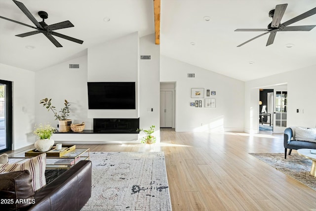 living area featuring ceiling fan, beamed ceiling, light wood-type flooring, and visible vents