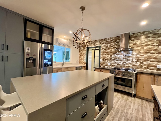 kitchen featuring a kitchen island, appliances with stainless steel finishes, sink, hanging light fixtures, and wall chimney range hood