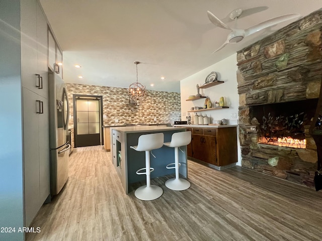 kitchen with hanging light fixtures, a fireplace, light hardwood / wood-style floors, and stainless steel fridge with ice dispenser