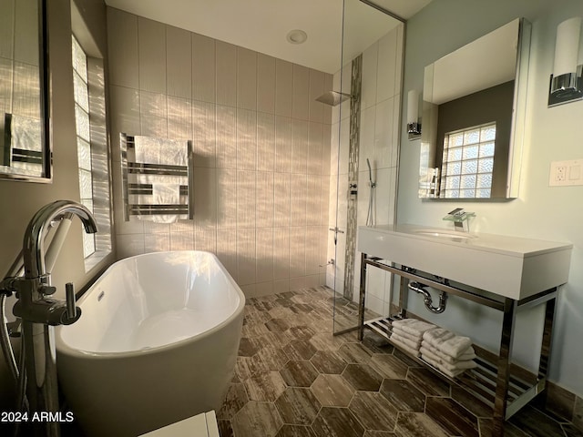 bathroom with independent shower and bath, sink, and tile walls