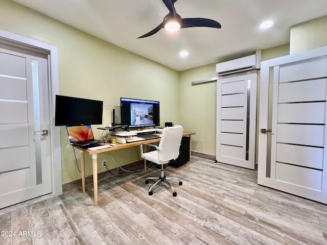 home office featuring a barn door, ceiling fan, an AC wall unit, and light hardwood / wood-style floors