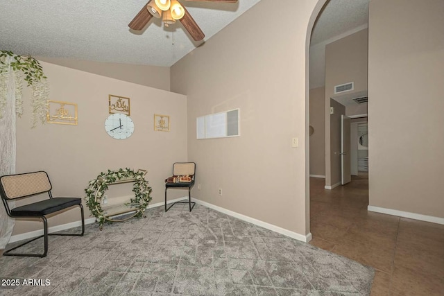 living area featuring ceiling fan, high vaulted ceiling, tile patterned floors, and a textured ceiling