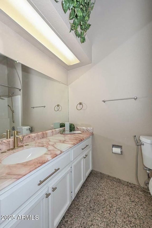 bathroom featuring toilet, vanity, and walk in shower