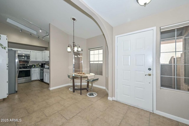 tiled foyer entrance with a chandelier and lofted ceiling