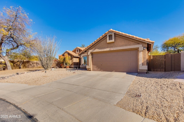 ranch-style home featuring a garage, concrete driveway, a tile roof, fence, and stucco siding