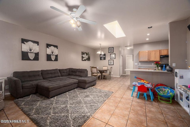 living area with a skylight, recessed lighting, a ceiling fan, light tile patterned flooring, and baseboards