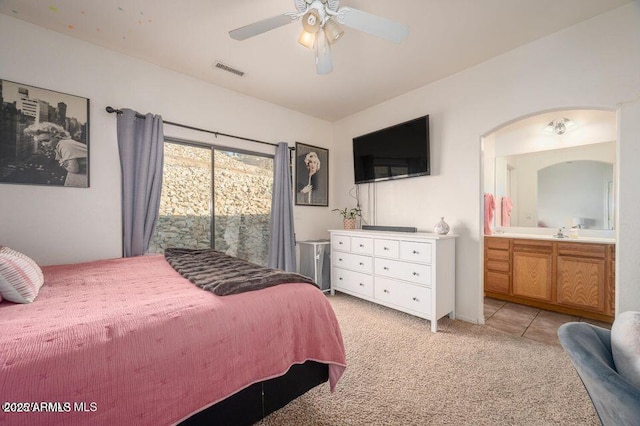 bedroom featuring light colored carpet, visible vents, ensuite bathroom, a ceiling fan, and a sink