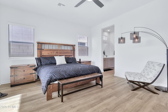 bedroom with ceiling fan, ensuite bathroom, and light wood-type flooring