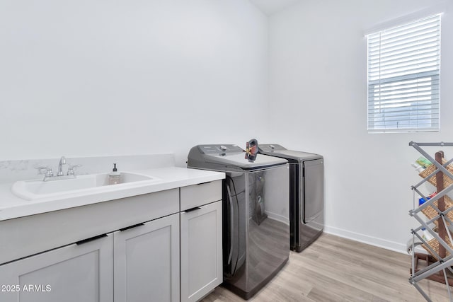 laundry area featuring sink, light hardwood / wood-style flooring, cabinets, and independent washer and dryer