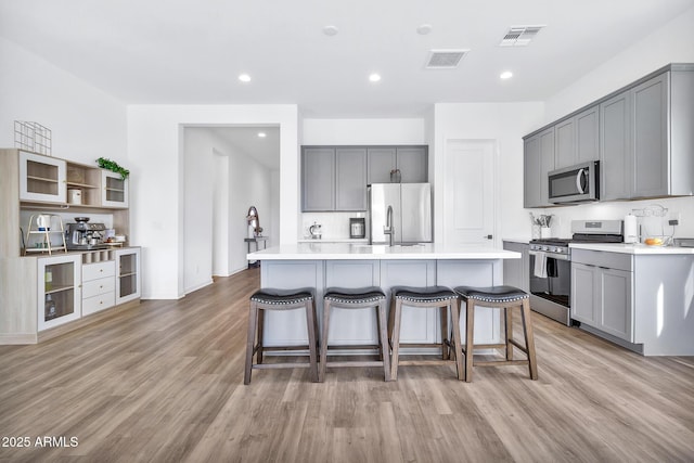 kitchen featuring stainless steel appliances, a center island, light hardwood / wood-style flooring, and gray cabinetry