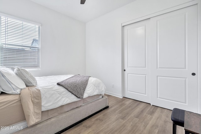 bedroom featuring ceiling fan, a closet, and light wood-type flooring