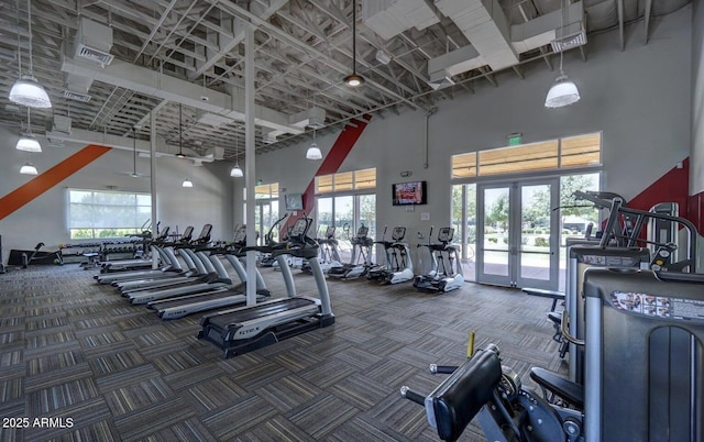 gym with dark carpet, french doors, and a high ceiling