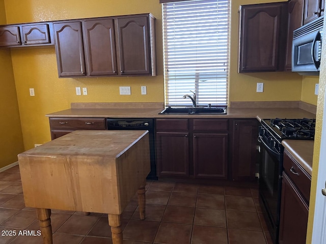 kitchen with dark tile patterned flooring, sink, dark brown cabinetry, and black gas range oven