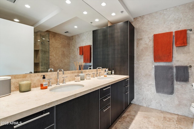 full bath featuring double vanity, a sink, recessed lighting, and tile walls