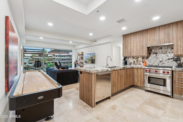 kitchen with visible vents, a peninsula, open floor plan, a sink, and stainless steel appliances