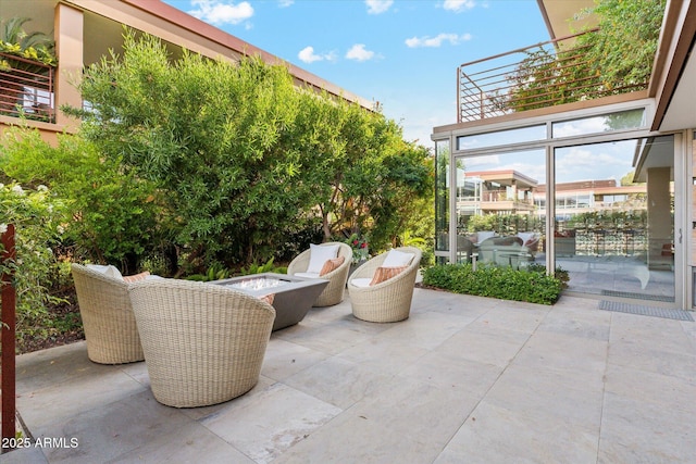 view of patio with a fire pit and a balcony