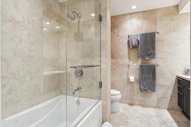 full bathroom featuring tile walls, vanity, toilet, and shower / bath combination with glass door