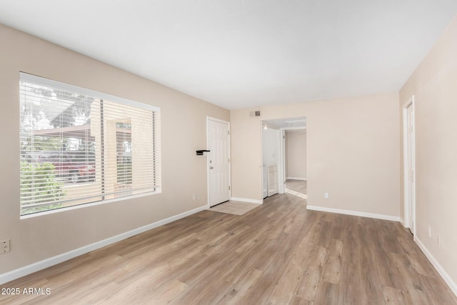 empty room with light wood-type flooring, visible vents, and baseboards