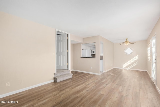 empty room featuring ceiling fan, light wood-style flooring, and baseboards