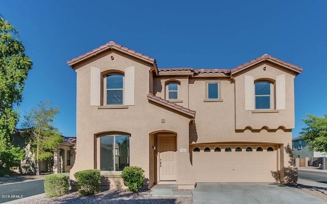 mediterranean / spanish-style home featuring a garage, concrete driveway, a tile roof, and stucco siding