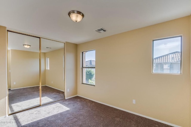 unfurnished bedroom with a closet, carpet, visible vents, and baseboards