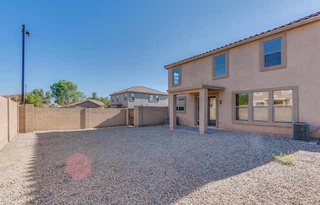 rear view of house with central air condition unit, a patio area, a fenced backyard, and stucco siding